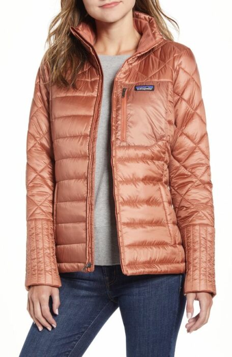 Chica con chaqueta coral, blusa gris y jeans oscuros
