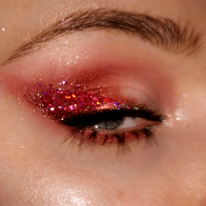 maquillaje con sombras rosas, guindas, moradas con glitter rosa y delineado negro