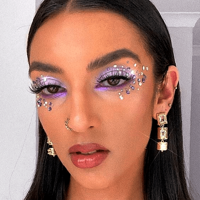 chica morena usando sombras plateadas, lilas, moradas y rosas, con glitter plateado en forma de estrellas pequeñas
