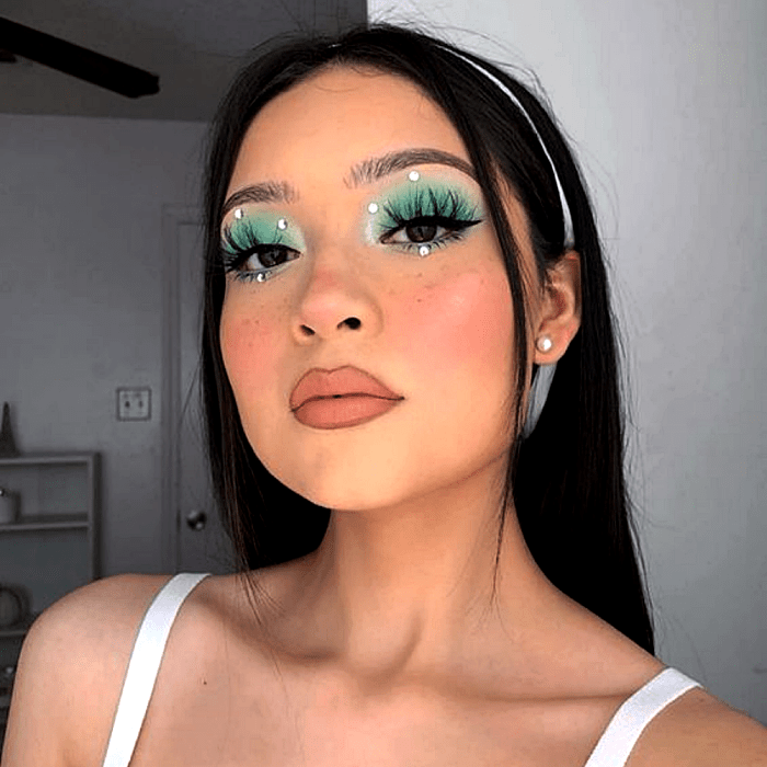 chica de cabello oscuro usando sombra verde, con delineado negro y pestañas postizas