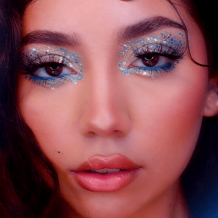 chica con maquillaje con glitter plateado, delineado gráfico, sombras azules, plateadas y celestes