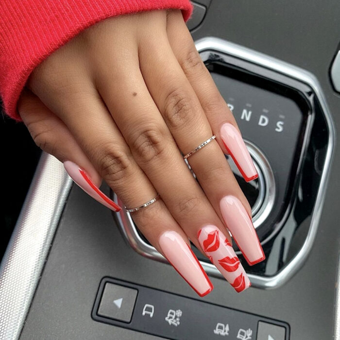 Manos de mujer con uñas largas cuadradas de bailarina pintadas en nude, rosa, con diseño de manicura francesa y besos rojos