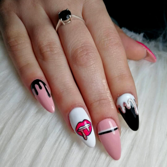 Manos de mujer con uñas largas stiletto pintadas en rosa bebé, negro y blanco, con diseño de labios con glitter