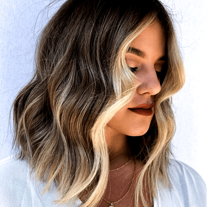 chica de cabello castaño con lipstick rojo y mechas y hightlights estilo money piece doradas