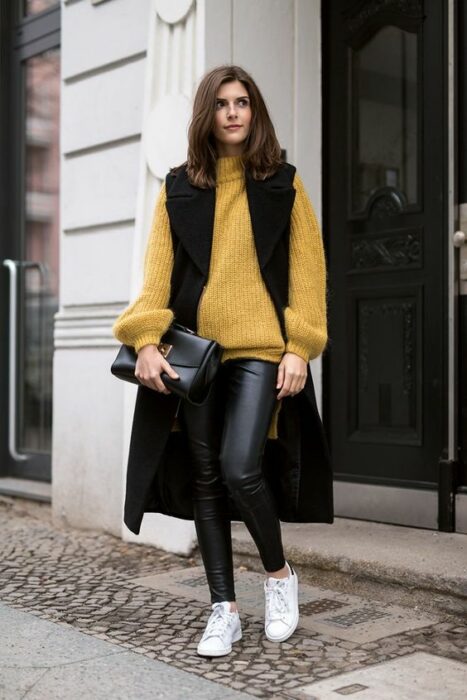 Chica llevando chaleco oversize de gamuza con suéter amarillo; ideas para llevar chaleco durante el otoño-invierno