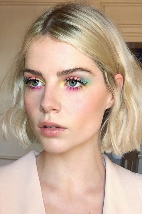 Chica rubia de tez pálida, con maquillaje de sombras en colores pastel amarillo, rosa, verde y azul