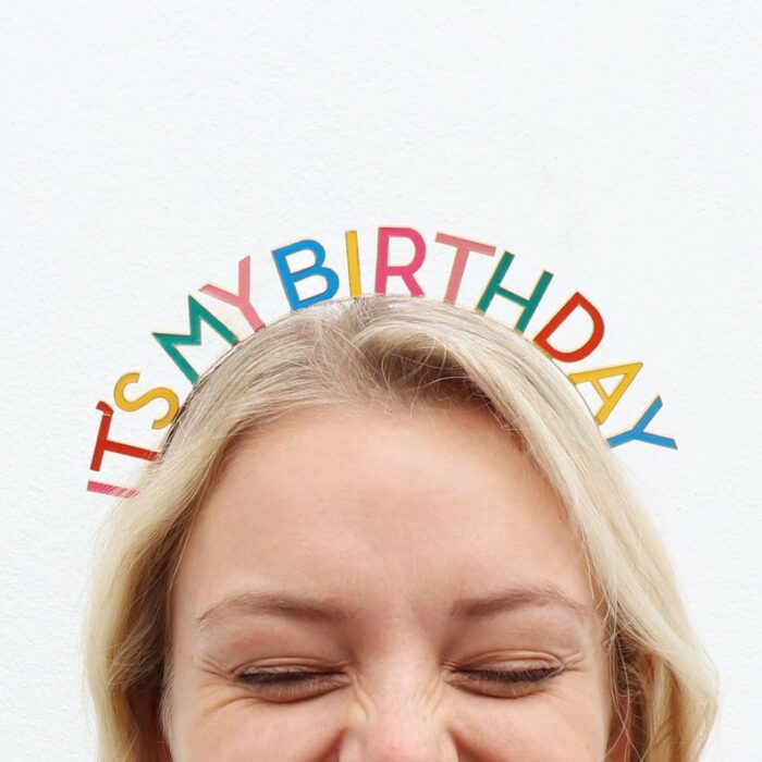 Chica rubia con diadema de colores que dice it's my birthday