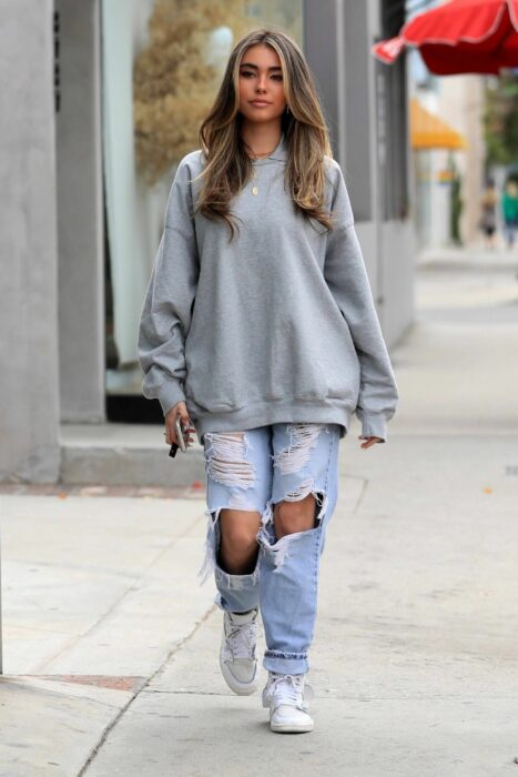 Chica usando jeans y una sudadera mientras va caminando por la calle