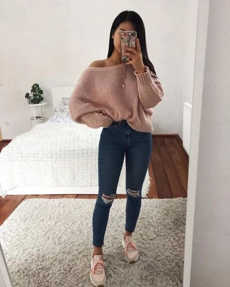 Chica usando jeans, suéter grande de color rosa y tenis de color blanco