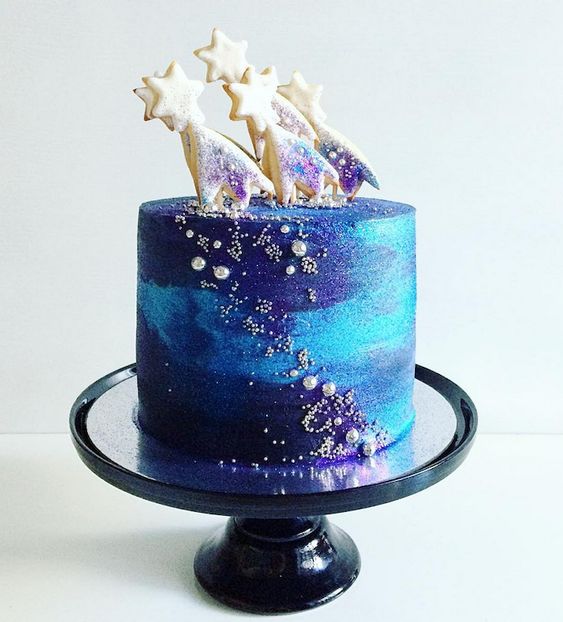 Pastel de un piso adornado con glaseado en tonos azul y morado, con estrellas de chocolate blanco; Pasteles inspirados en la galaxia