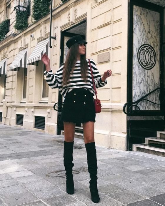 Chica de cabello largo con falda negra y blusa de rayas blancas y negras y gorro