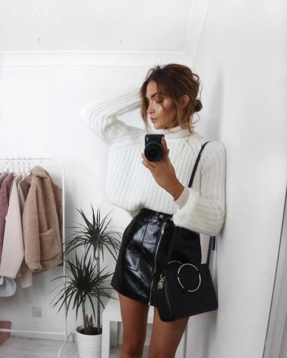 Chica tomándose una selfie con suéter blanco y falda negra