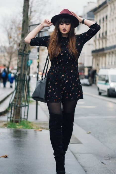 Chica con sombrero guinda, medias, botines negros y vestido negro con lunares blancos