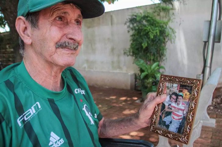Altamir Soares de Oliveira mirando fotos de su hijo