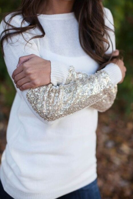 Chica con suéter blanco decorado con lentejuelas plateadas