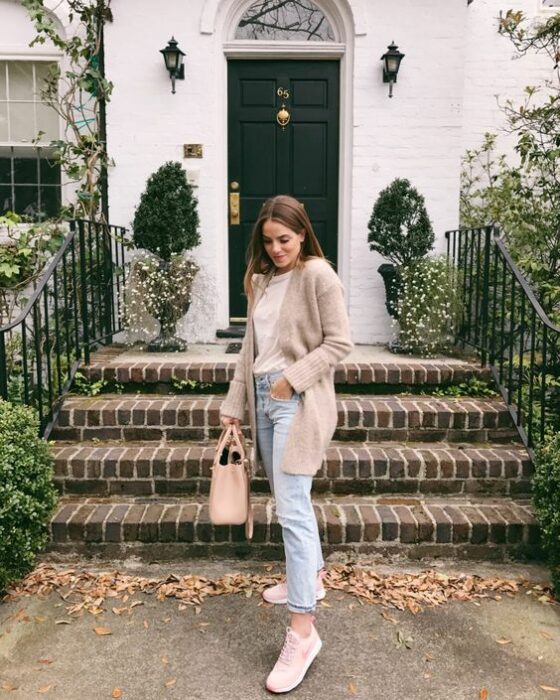 Chica usando mom jeans tenis, blusa color hueso de cuello alto y cardigan color beige