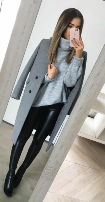 Chica usando leggings y botines negros, con suéter de cuello alto color azul cielo y abrigo largo color gris
