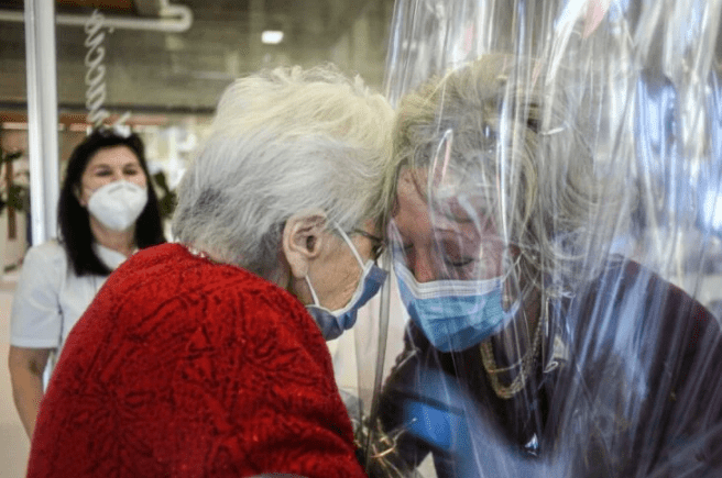 Anciana abraza a su hija por medio de plástico de seguridad en asilo