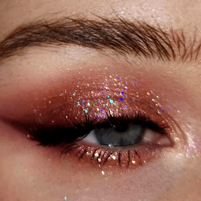 maquillaje de ojos con sombras rosas y cafés, glitter multicolor, delineado color guinda