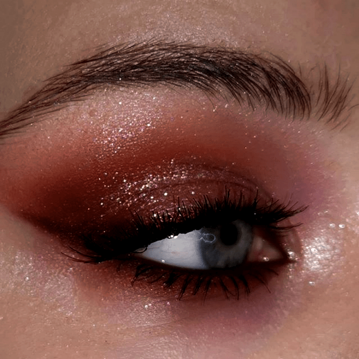 maquillaje de ojos con sombras cafés, rojas, guindas y rosas, delineado sutil y rímel negro