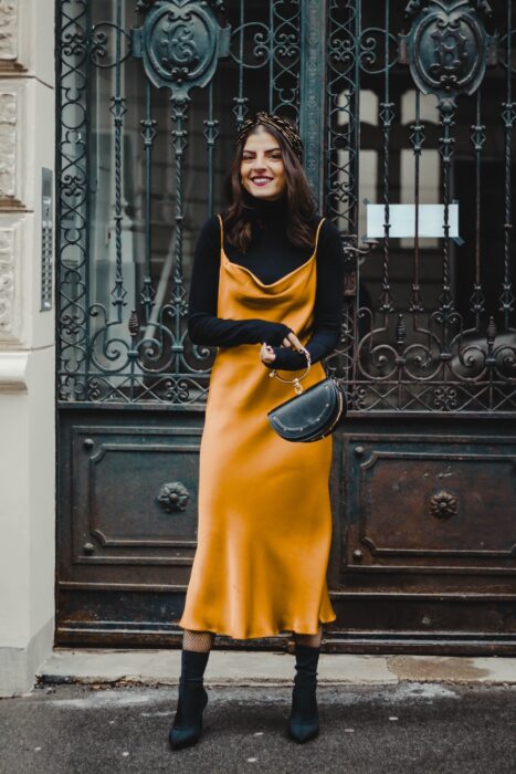 Chica usando un vestido de color mostaza con una blusa de cuello de tortuga y botines