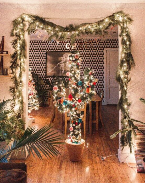 Árbol de navidad en forma de cactus en el comedor con ramas de pino y luces decorando el techo