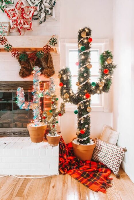 Árboles de navidad en forma de cactus en verde y blanco en una sala cercana a una chimenea