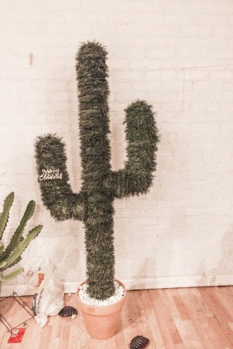 Árbol de navidad en forma de cactus sin decoración frente a una pared blanca