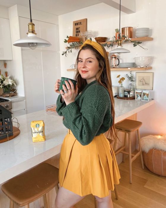 Chica con minifalda amarilla y suéter verde; ideas para usar minifalda con suéter en otoño-invierno