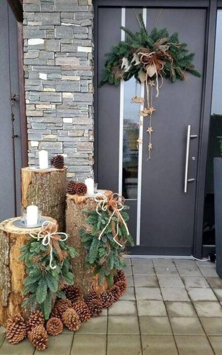 Puerta decorada con troncos y velas y una corona