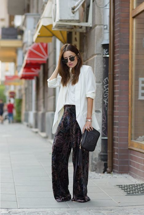 Chica de cabello largo con blusa y blazer blancos y pantalón negro de terciopelo