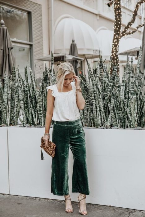 Chica rubia con blusa blanca y pantalón verde esmeralda de terciopelo