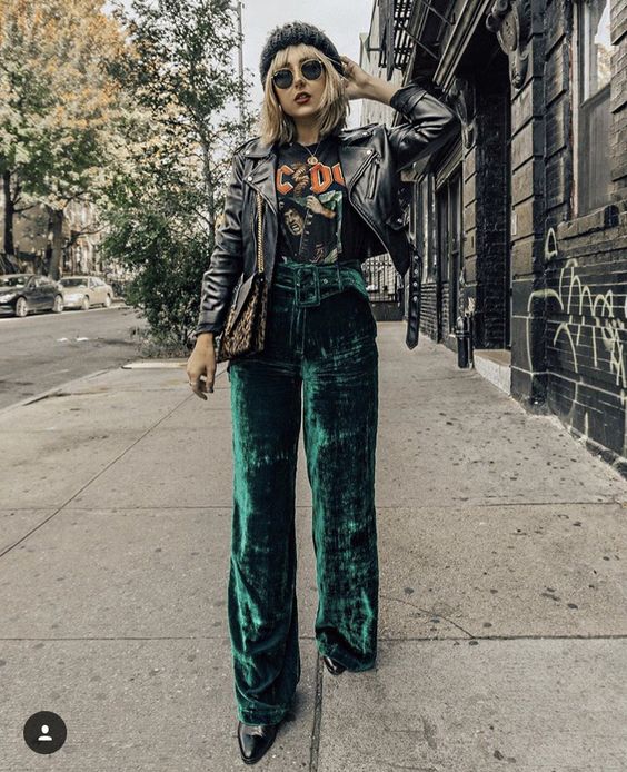 Chica rubia con blusa negra y pantalón verde esmeralda de terciopelo y saco gris