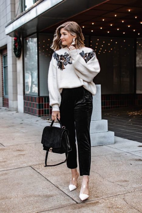 Chica rubia con pantalón negro y sudadera blanca con detalles en los hombros