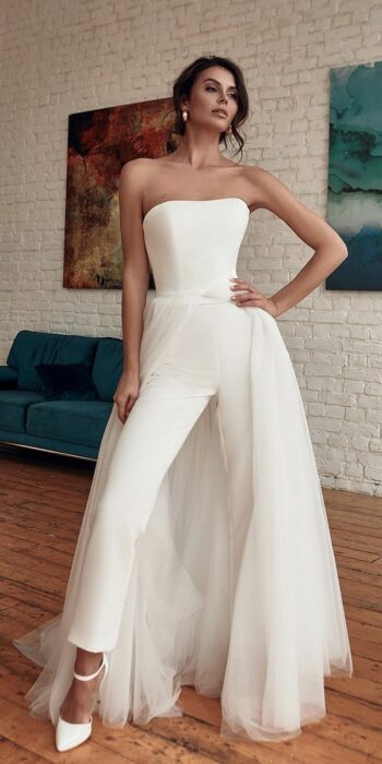 Chica con un traje de novia estilo pantalón y capa trasera