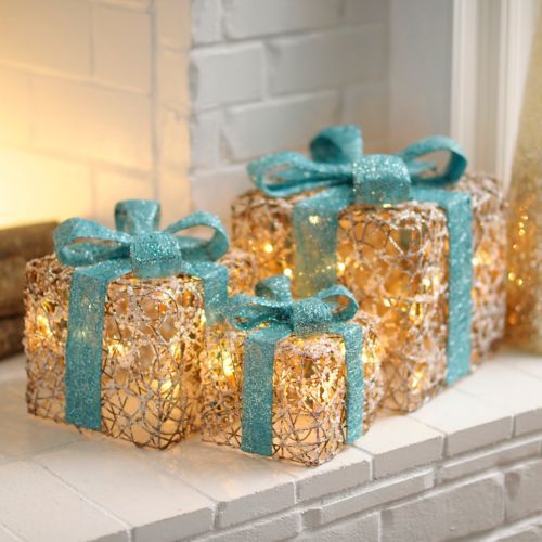 Regalos decorativos con material de estambre y luces navideñas en el interior, con un gran lazo turquesa por encima