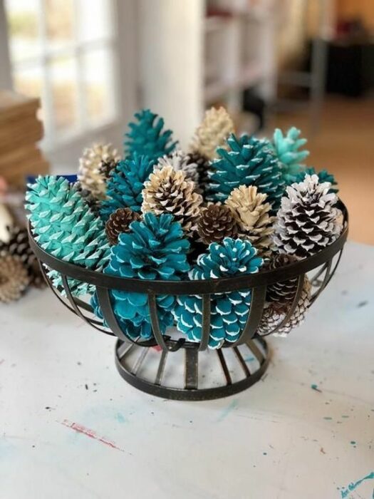 Cesta de centro de mesa con piñas de pino pintadas de color turquesa