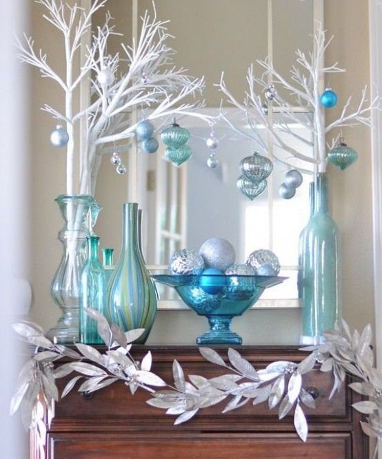 Mueble café con cuatro jarrones azul turquesa conteniendo ramas blancas y esferas azules
