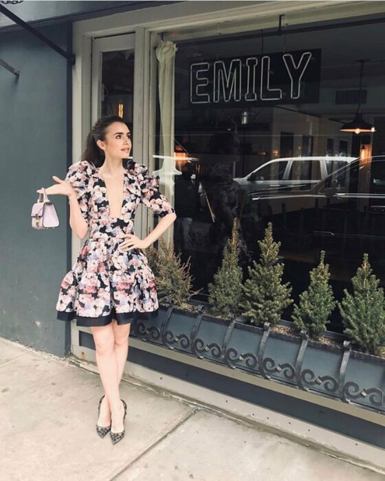 Lily Collins usando un vestido floreado con negro en una escena de Emily in Paris