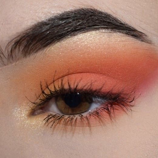 Maquillaje de ojos con sombras naranjas, rosas, amarillas y un toque iluminador en el lagrimal
