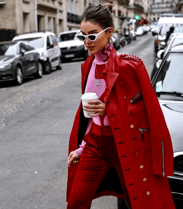 mujer de cabello oscuro con suéter rosa de cuello alto, abrigo largo rojo, y pantalones rojos