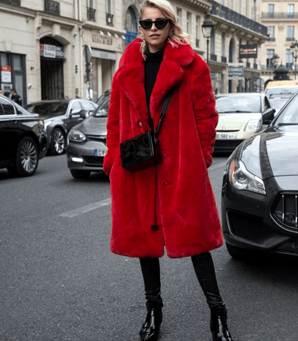 mujer rubia con abrigo rojo afelpado, top negro y jeans negros