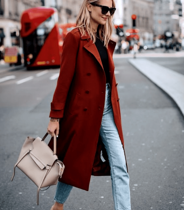 mujer rubia con top negro, abrigo rojo y jeans a la cintura