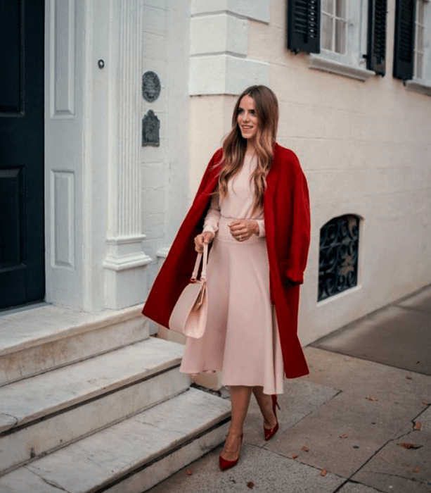 mujer rubia con vestido rosa y abrigo rojo, bolso rosa y tacones rojos