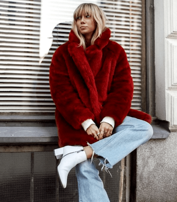 mujer rubia con abrigo rojo afelpado, jeans holgados y top blanco