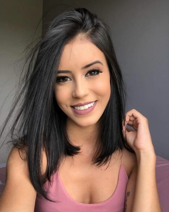 Chica morena sonriente con cabello lacio y blusa de tirantes blanca