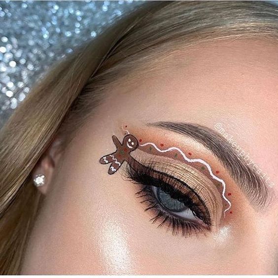 Chica con maquillaje de ojos color café, con un muñeco de jengibre colgando; Maquillajes lindos para celebrar Navidad