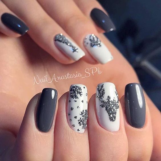 Uñas pintadas en tonos gris y blanco con diseños de renos navideños en plateado; diseños de manicuras navideñas