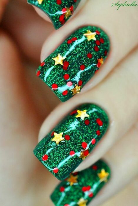 Uñas con base verde y decoraciones de glitter y estrellas amarillas; diseños de manicuras navideñas