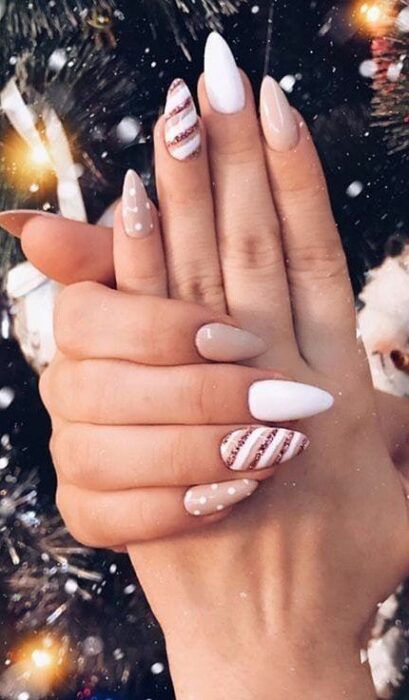 Uñas en forma de pico con base blanca y relieves en rojo; diseños de manicuras navideñas